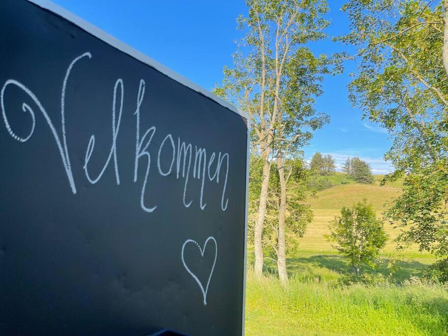 a sign with a heart painted on it in a field at Tiny House i storslået natur in Frederikshavn