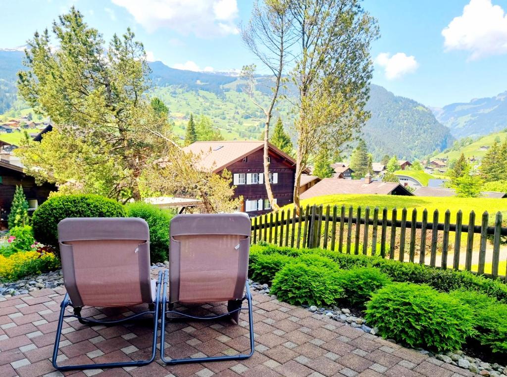 two chairs sitting on a patio in front of a fence at MOM - Alpine Boutique Apartments, Chalet Fagus, Terrace Studio in Grindelwald