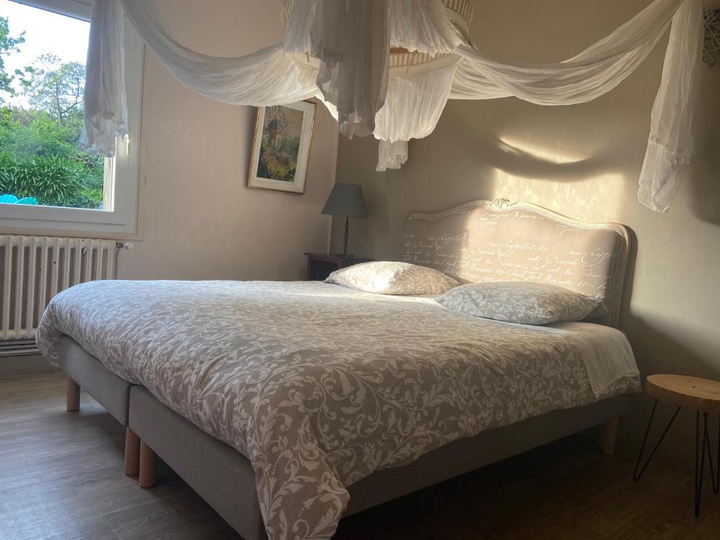 - une chambre dotée d'un grand lit avec des draps blancs et une fenêtre dans l'établissement Havre de paix de 100M2, à Perros-Guirec