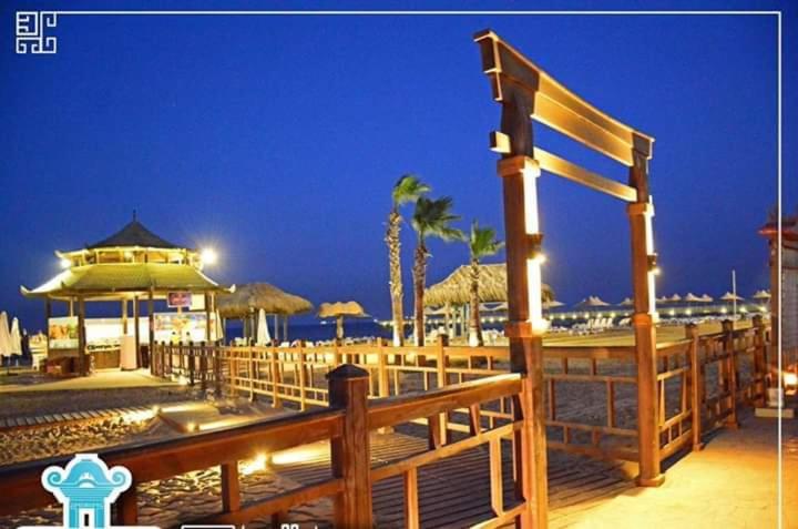 a boardwalk with umbrellas on the beach at night at فيلا في بلو باي أسيا العين السخنة in Ain Sokhna