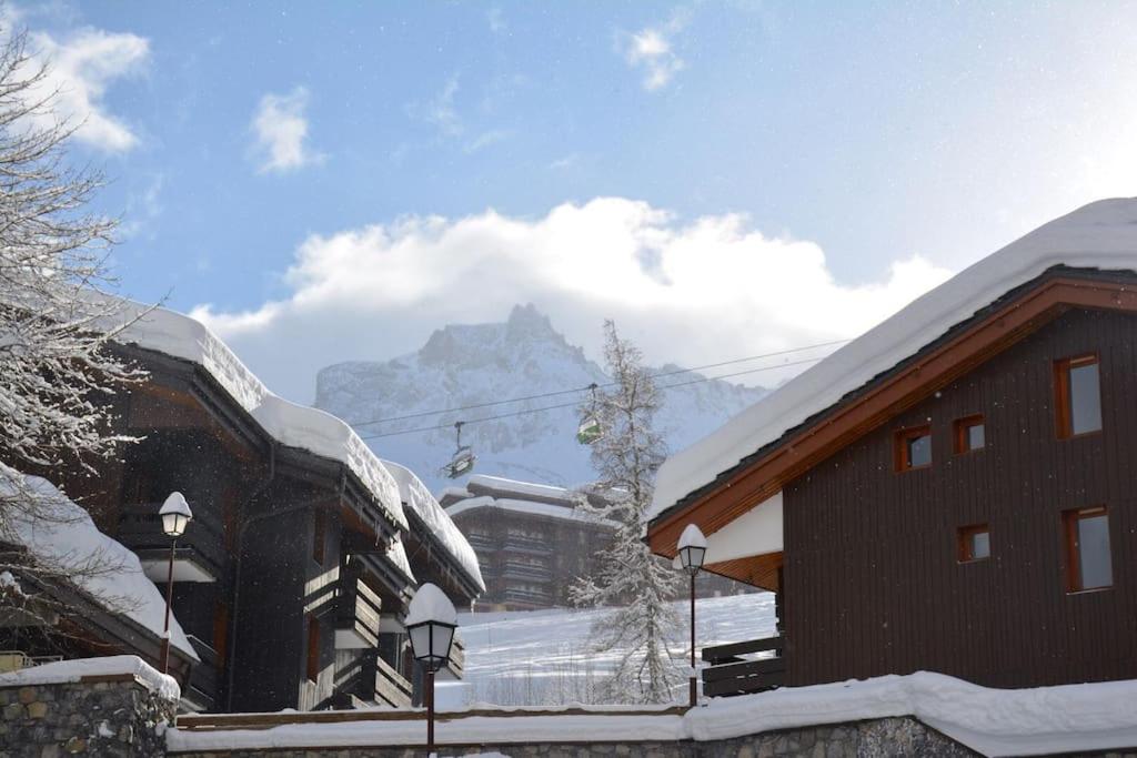 un bâtiment recouvert de neige avec une montagne en arrière-plan dans l'établissement Stijlvol 4-kamerappartement in Valmorel aan de piste, à Valmorel