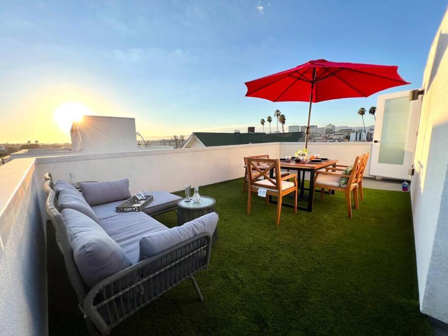 a patio with a couch and a table and an umbrella at Luxury K-Town Dwelling with private rooftop deck. in Los Angeles