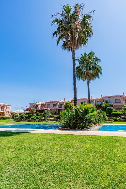 a swimming pool with palm trees and grass at Casa Colina 2 in Albufeira