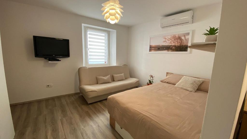 1 dormitorio con 1 cama, 1 silla y TV de pantalla plana en Apartma Pingo, en Koper