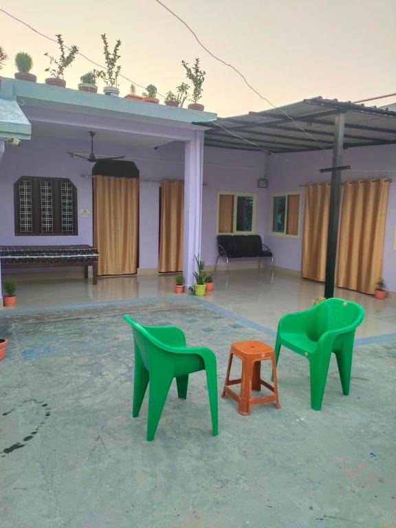 two green chairs and a table in front of a house at Krishna Kunj Homestay Rishikesh in Rishīkesh