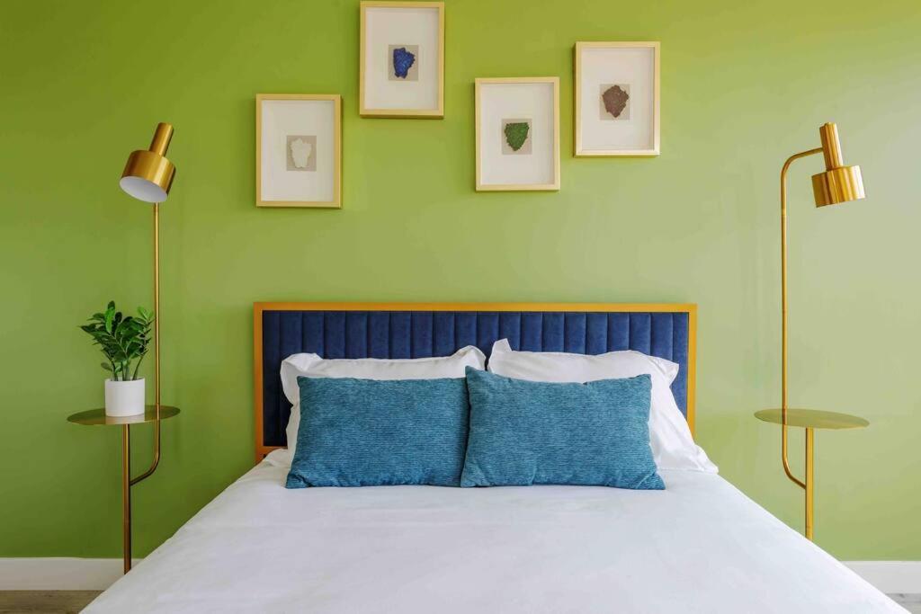 a bedroom with green walls and a bed with blue pillows at Hollywood Art House with Bright Sunlight in Los Angeles
