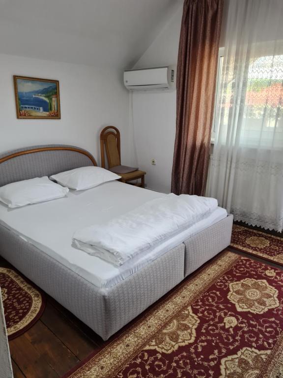 1 dormitorio con cama blanca y ventana en Pensiunea Clasic en Gherla