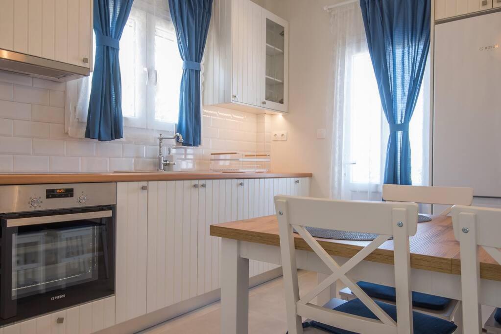 una cucina con tende blu e tavolo e sedie di MFP Dryos Paros House Project a Drios