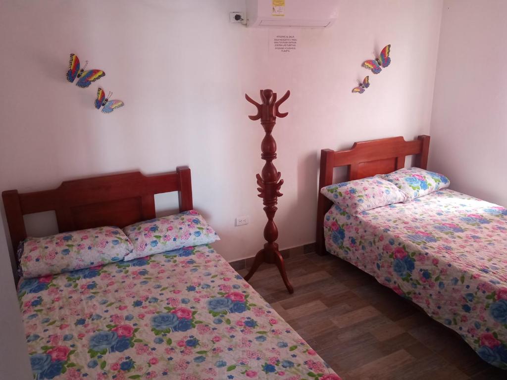 two beds in a bedroom with butterflies on the wall at Cabaña frente al mar Encanto del Viento in San Bernardo del Viento