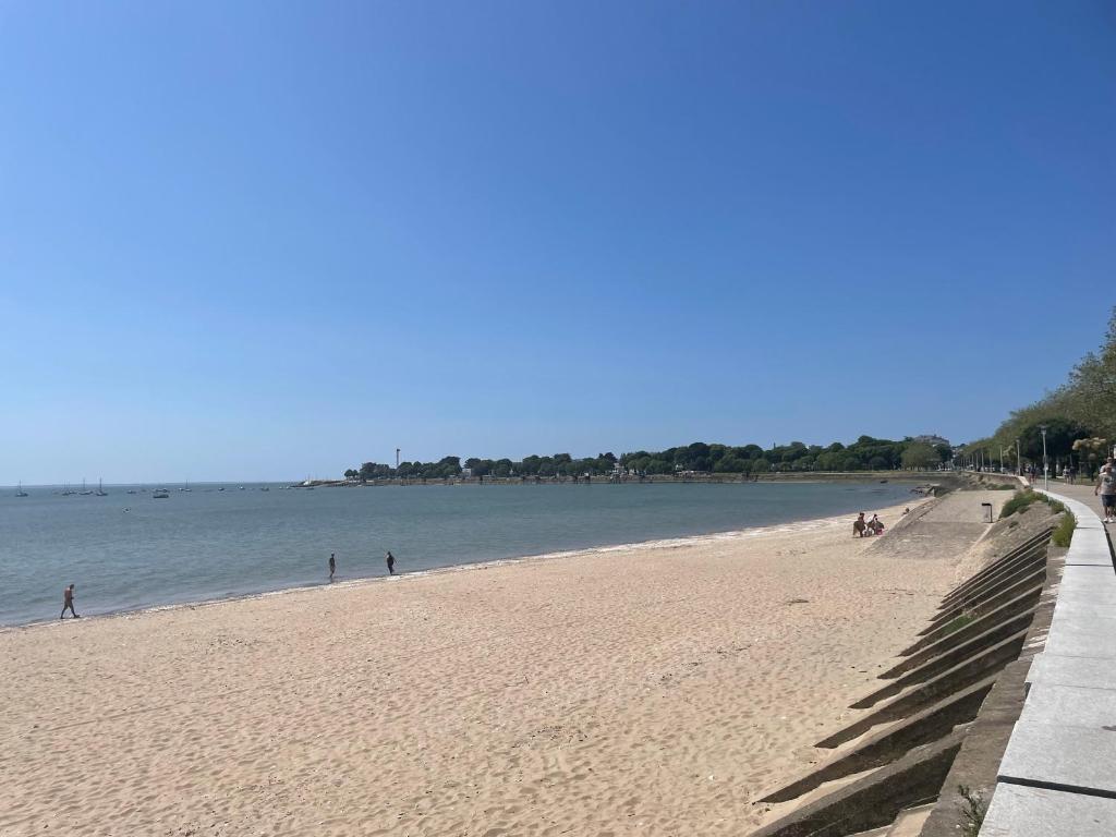 a beach with people walking on the sand and the water at Studio cosy avec terrasse, proche Chantiers et Airbus in Saint-Nazaire