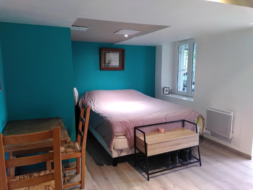 a bedroom with a bed and a blue wall at La chambre de la maison bleue in Colmar