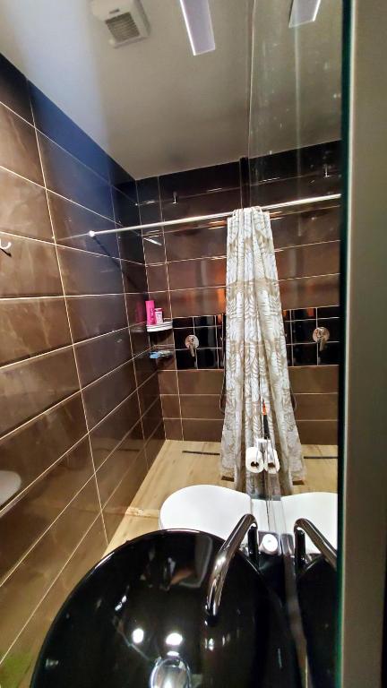Sirius Apartment في شكودر: حمام مع حوض أسود ومرآة