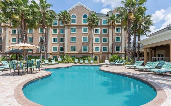 a pool in front of a hotel with chairs and an umbrella at Charming suite in a condotel close to Disney in Orlando