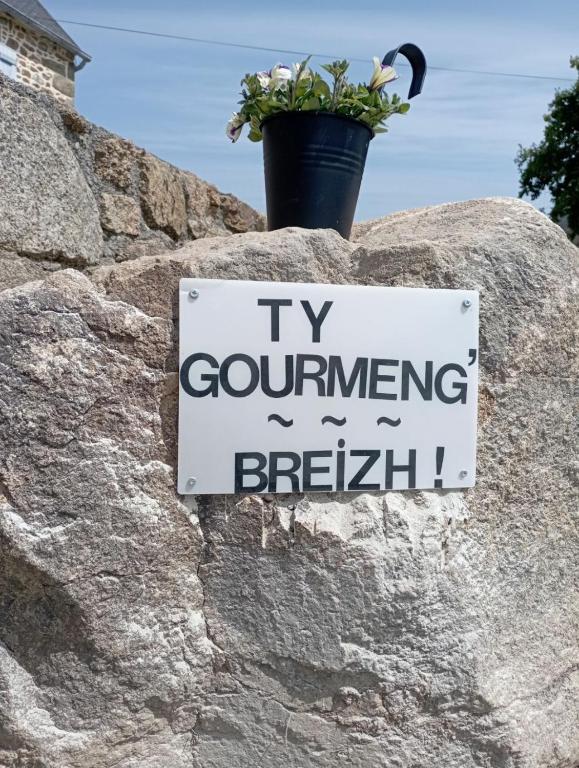 un panneau sur un rocher avec une plante en pot dessus dans l'établissement Gîte avec son bain nordique privatif au feu de bois, à Pleubian