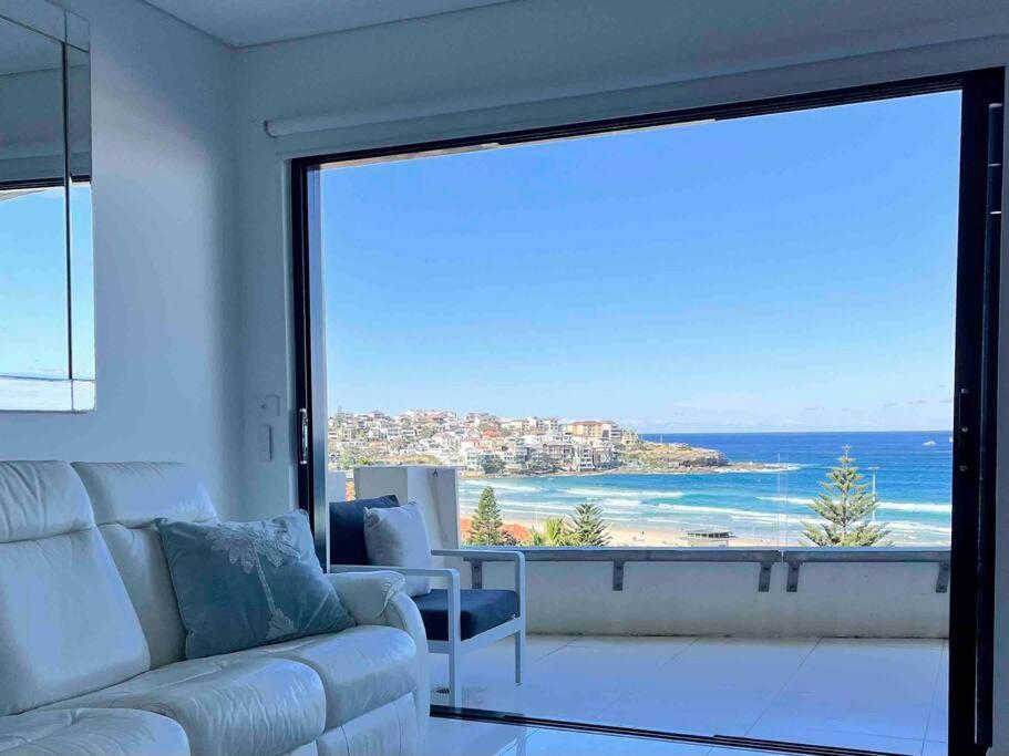a living room with a couch and a view of the ocean at Bondi Beach Waves Beachfront Apartment in Sydney
