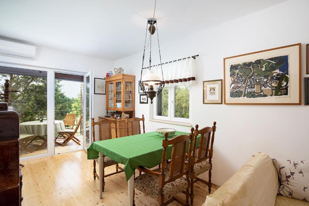 a dining room with a green table and chairs at Holiday Home Marko in Rebići