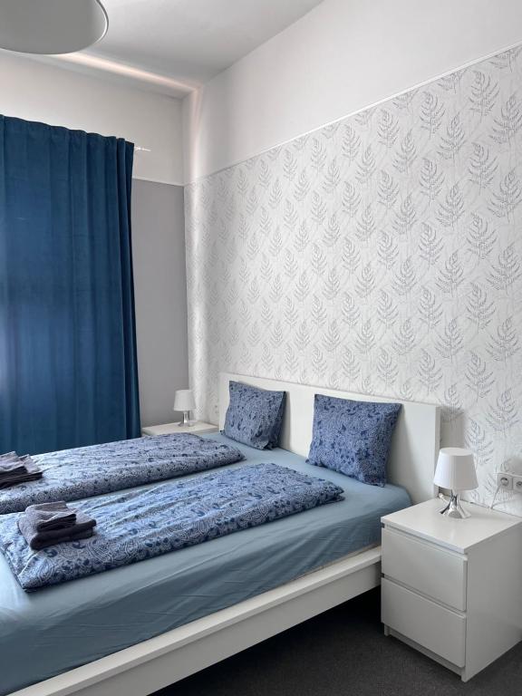 a bedroom with a bed with blue sheets and blue curtains at Downtown Apartments in Pilsen