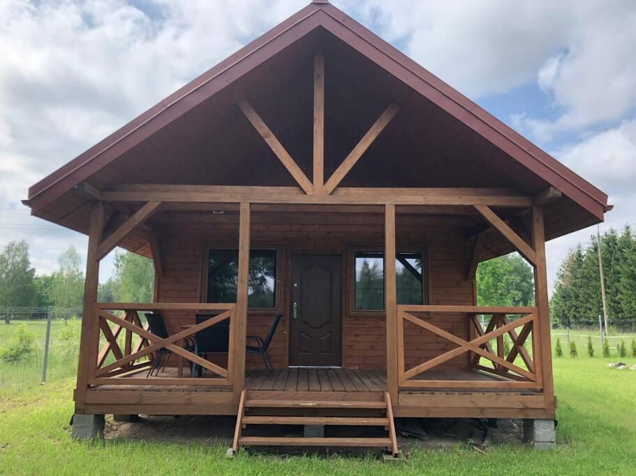 a log cabin with a large porch and a door at Domek letniskowy w Karwiku in Karwik