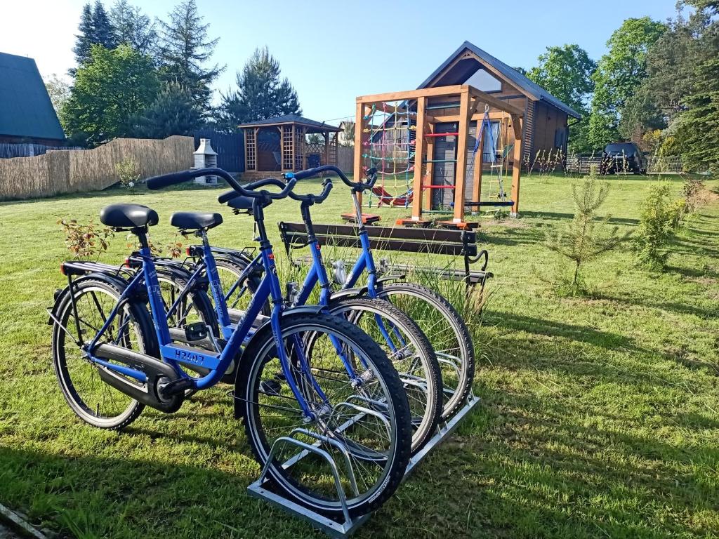 two bikes parked in the grass with a playground in the background at Słoneczne Mazury - Dom Wakacyjny in Piasutno