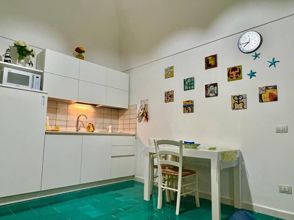 eine Küche mit einem Tisch und Stühlen sowie einer Uhr an der Wand in der Unterkunft un angolo di paradiso in Amalfi