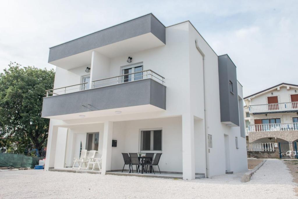 a white house with a balcony on the beach at Apartmani Marin D&A in Zaboric