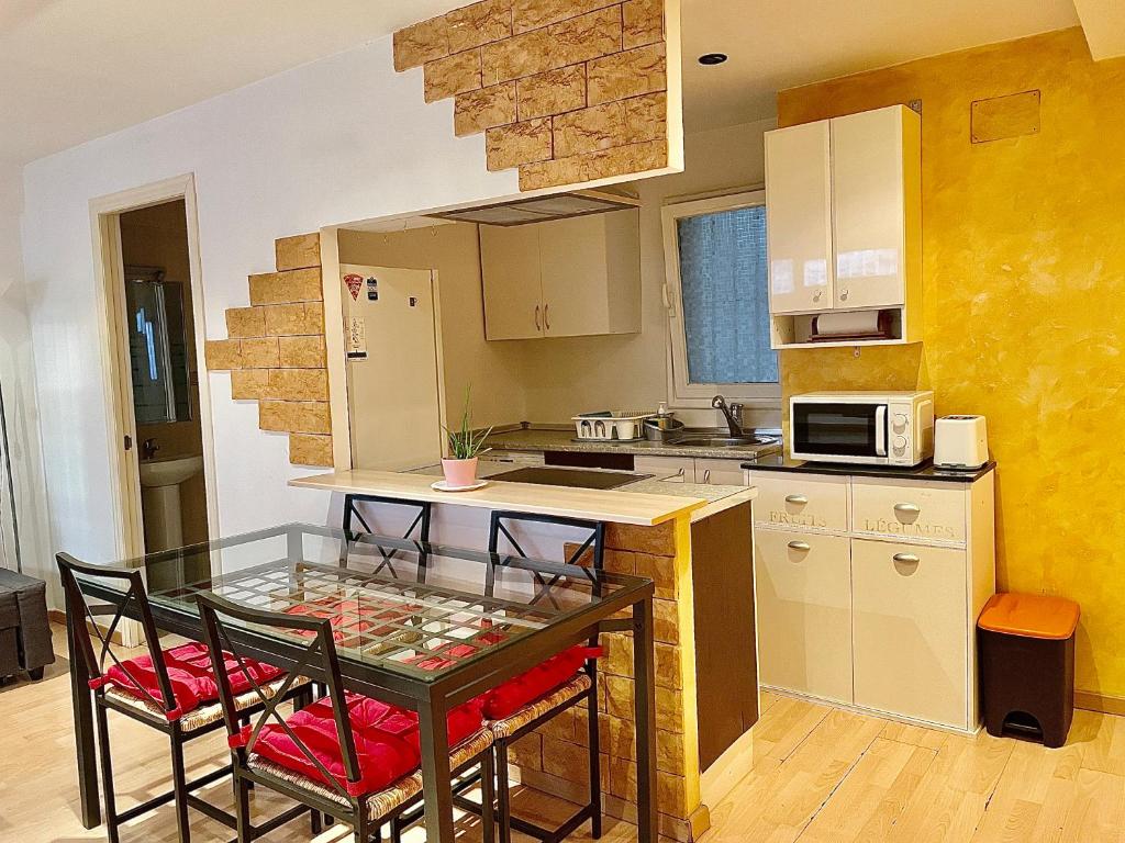 a small kitchen with a glass table and chairs at Acogedor Dúplex Barrio del Pilar in Madrid