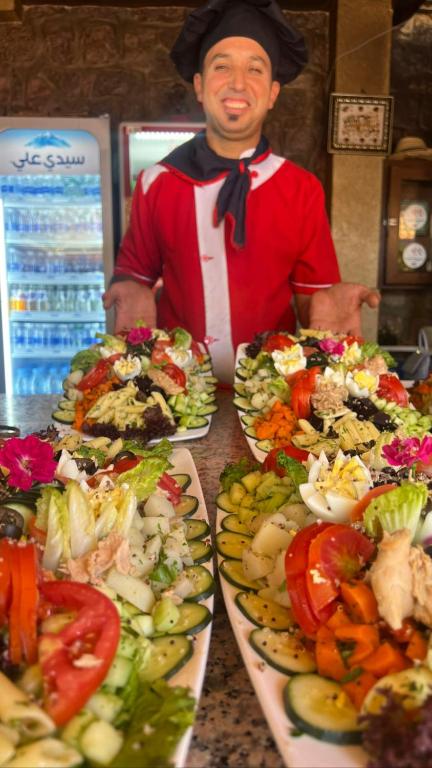 a man standing behind a table with plates of food at maison d'hôtes yamine in Beni Mellal
