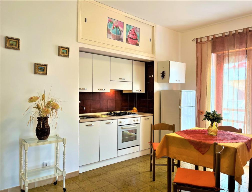 una cocina con armarios blancos y una mesa con mantel. en Casa MARINA, en Scalea