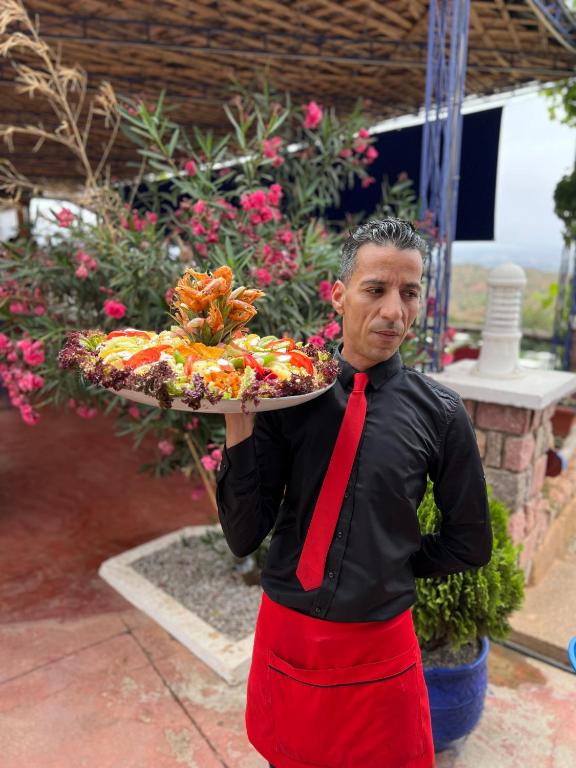 a man holding a tray of food on a plate at maison d'hôtes yamine in Beni Mellal