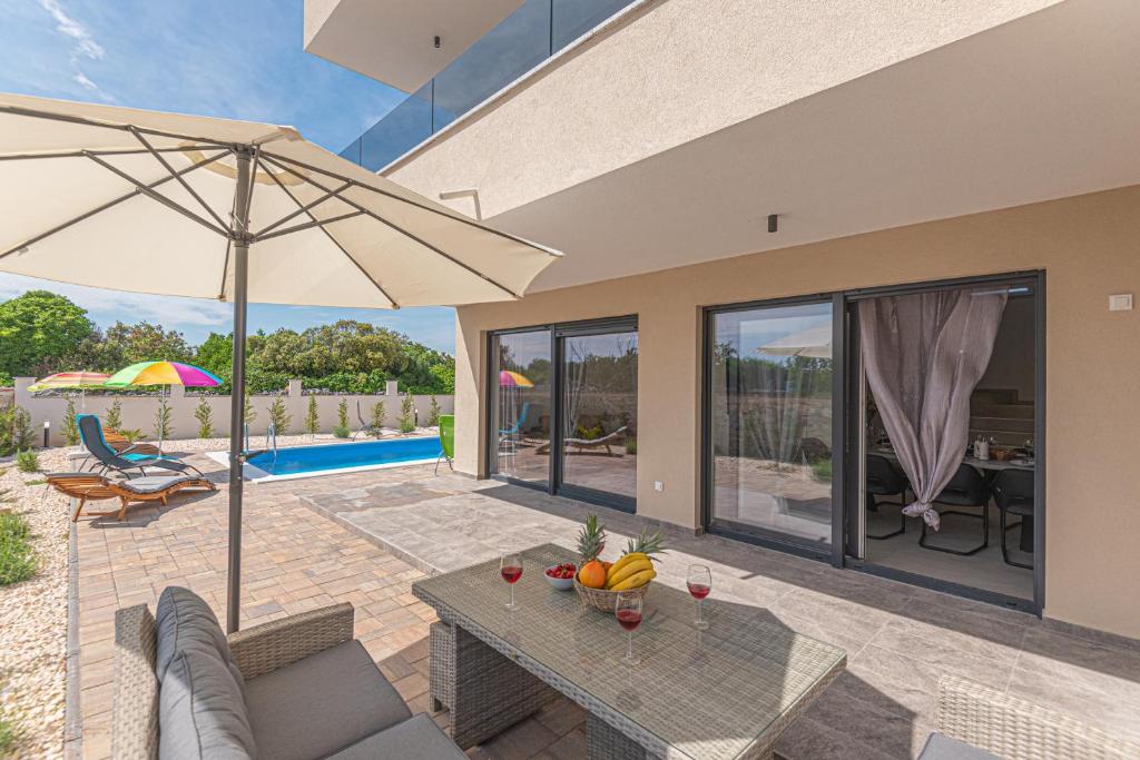 un patio con mesa y sombrilla en Villa Adriatic Sunset, en Jadrija