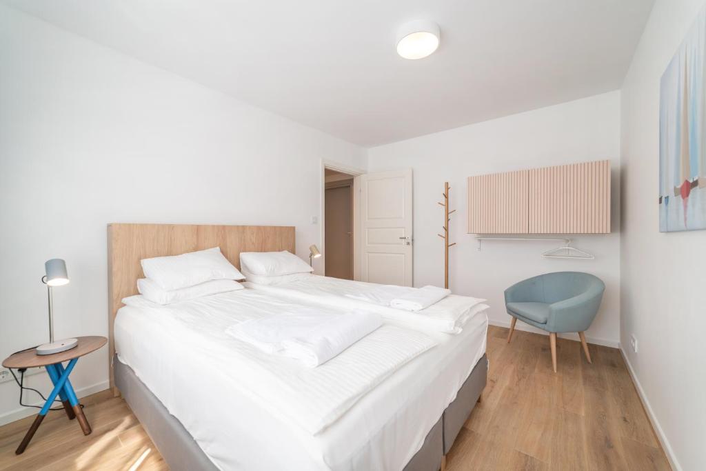 1 dormitorio con 1 cama blanca grande y 1 silla azul en Ogrodowa 45, en Jastarnia