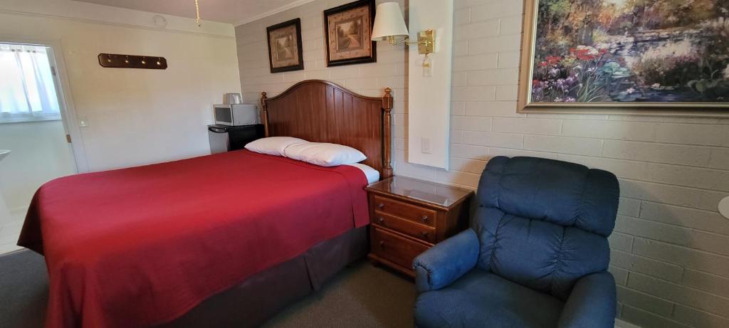a bedroom with a bed and a chair in it at Husker Inn in North Platte