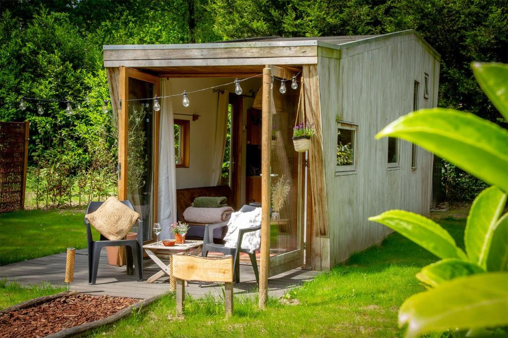 um barracão com uma mesa e cadeiras num quintal em Tiny House Hilver - uniek en sfeervol huisje middenin het bos em Diessen