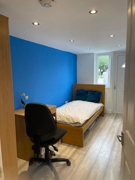 a bedroom with a blue wall and a desk and a chair at One Bedroom Self Catered Serviced Accommodation 10 Minutes from City Center in Edinburgh