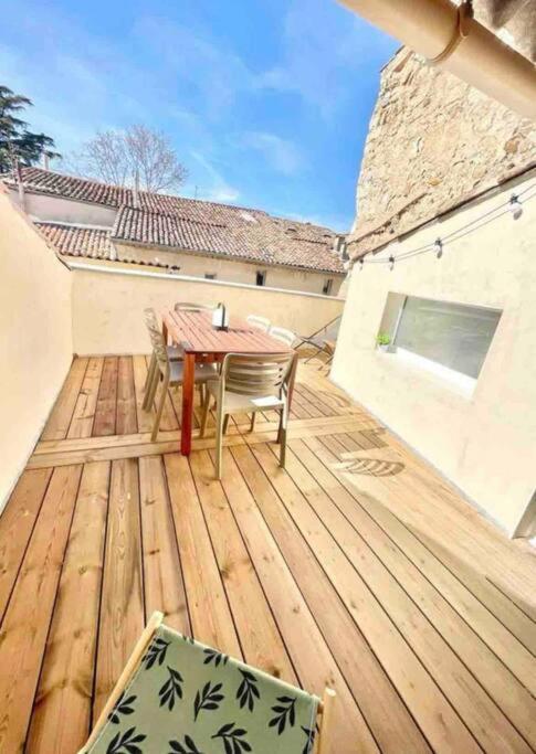 une terrasse en bois avec une table et des chaises dessus dans l'établissement Maison avec extérieur proche saint Guilhem le desert, à Saint-André-de-Sangonis