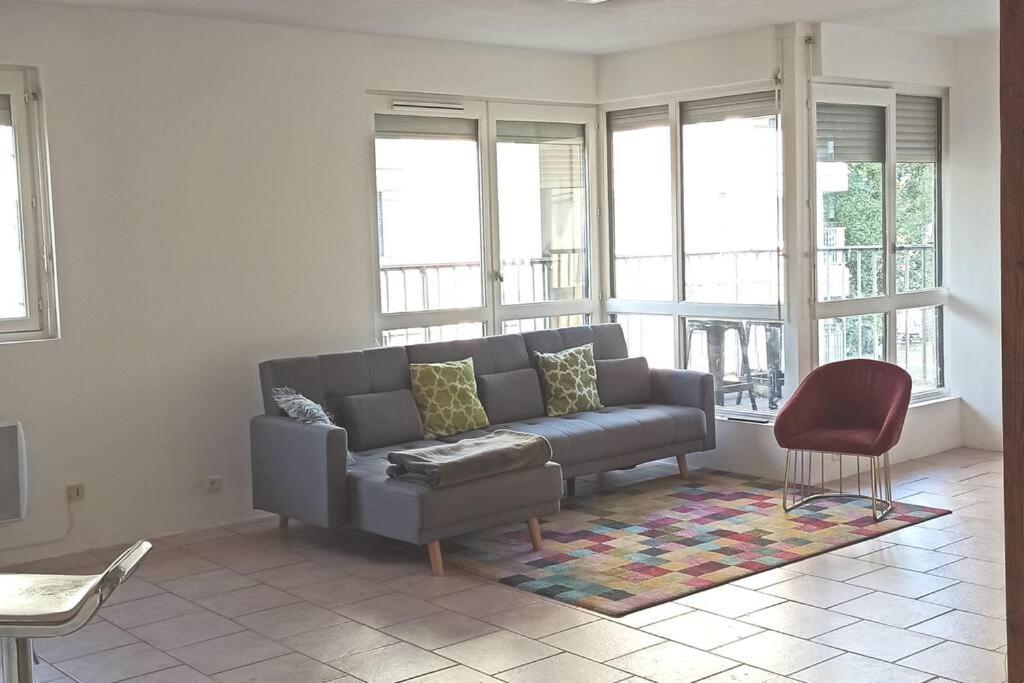 ein Wohnzimmer mit einem Sofa und einem roten Stuhl in der Unterkunft BEE COOL 75 m2 Le Verdon in Le Verdon-sur-Mer