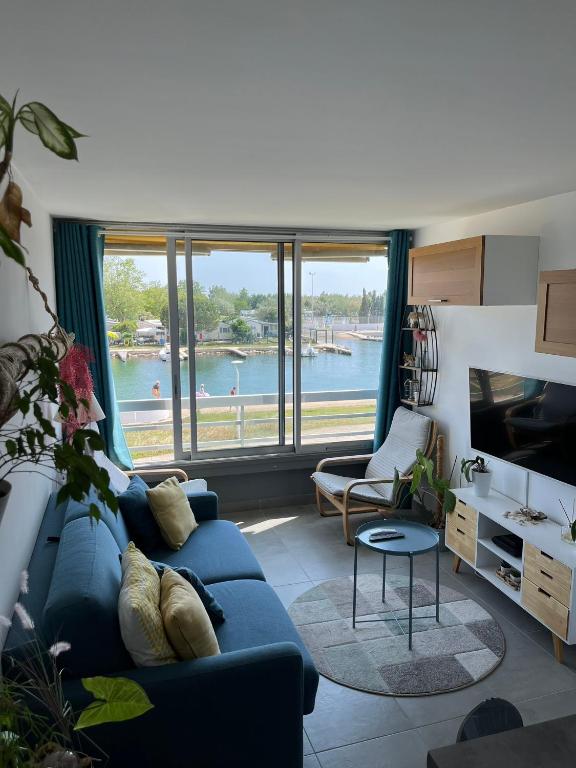 un salon avec un canapé bleu et une grande fenêtre dans l'établissement Studio port camargues, au Grau-du-Roi