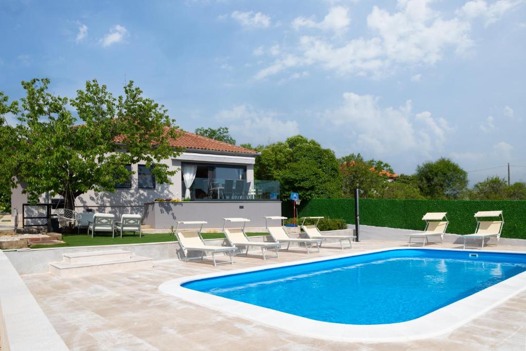 a swimming pool with chairs and a house at Villa Voyage in Zadar