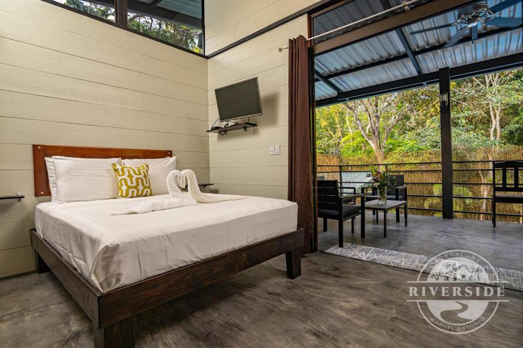 a bedroom with a bed and a tv on the wall at Riverside Villas in Manuel Antonio