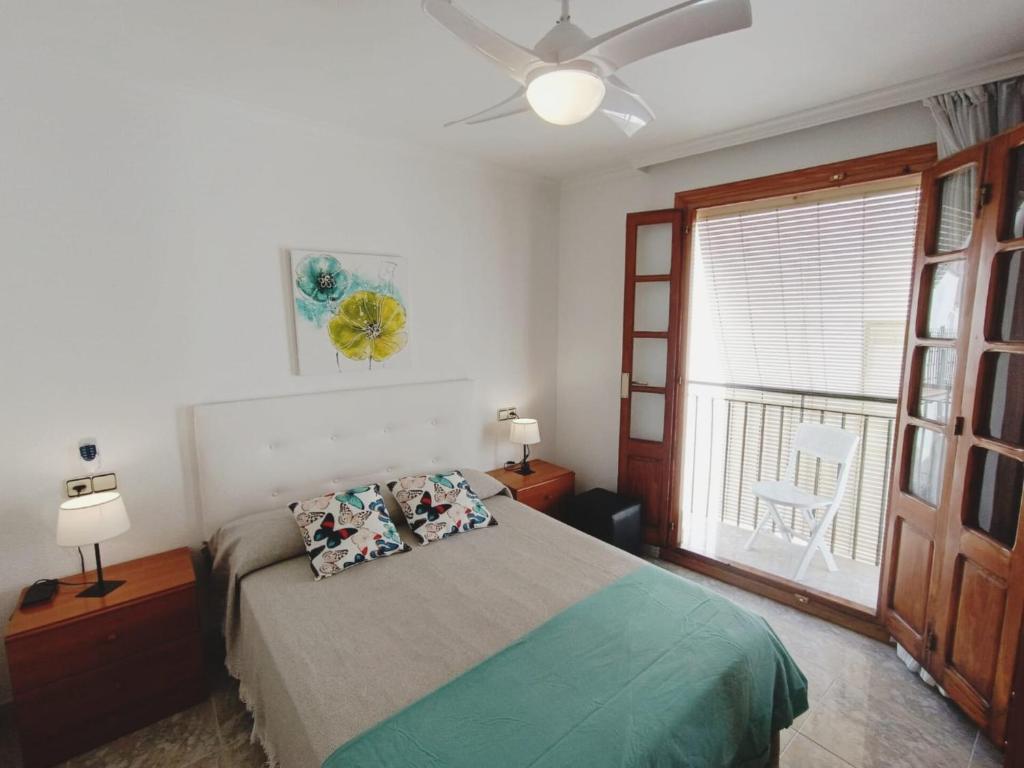 een slaapkamer met een bed, een plafondventilator en een raam bij NEW! BRISA MARINA Apartment, 1a Linea Puerto y Mar in Peñíscola
