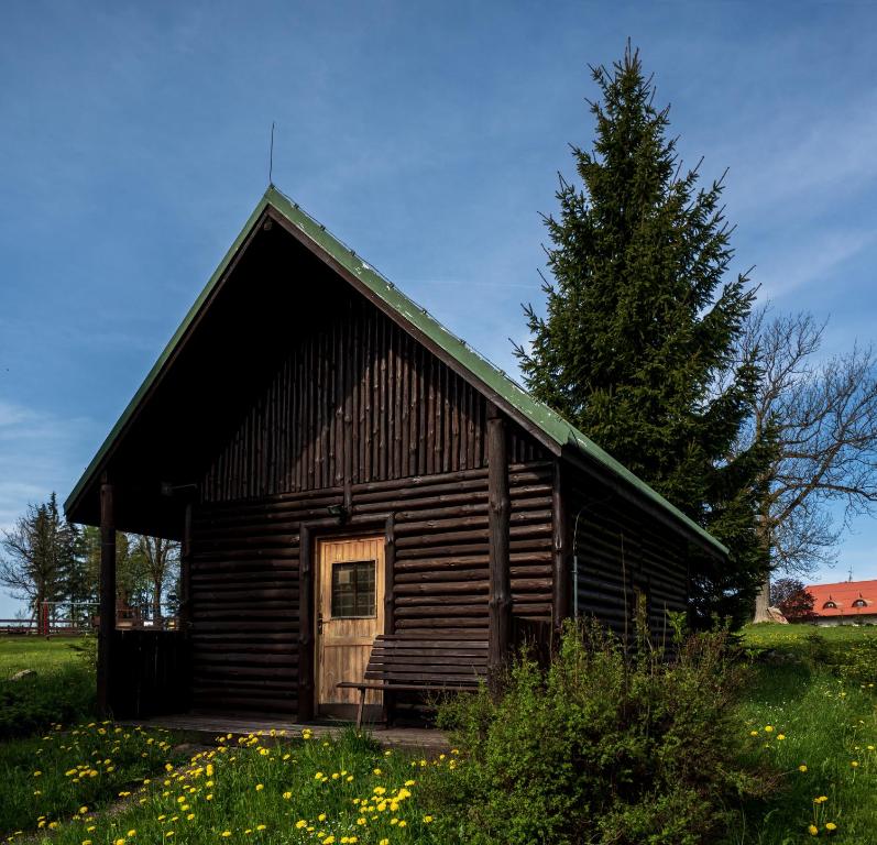 una vieja cabaña de madera con un árbol en un campo en Strážné Chalet en Strážné