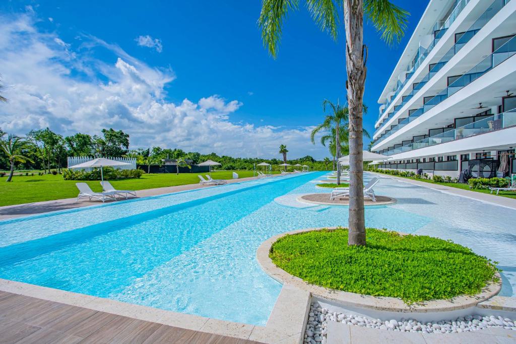 una piscina con una palmera frente a un edificio en Xeliter Cana Rock Punta Cana, en Punta Cana