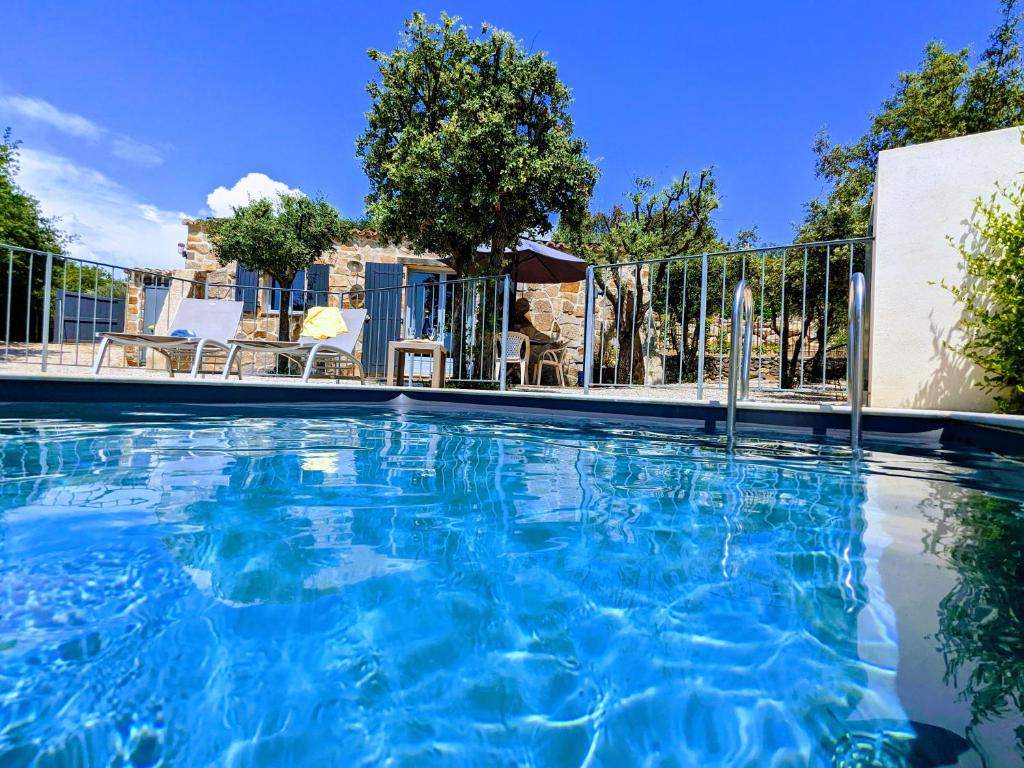 une piscine d'eau bleue en face d'une clôture dans l'établissement Charmant Gîte Mazet Lo Garric, à Caux