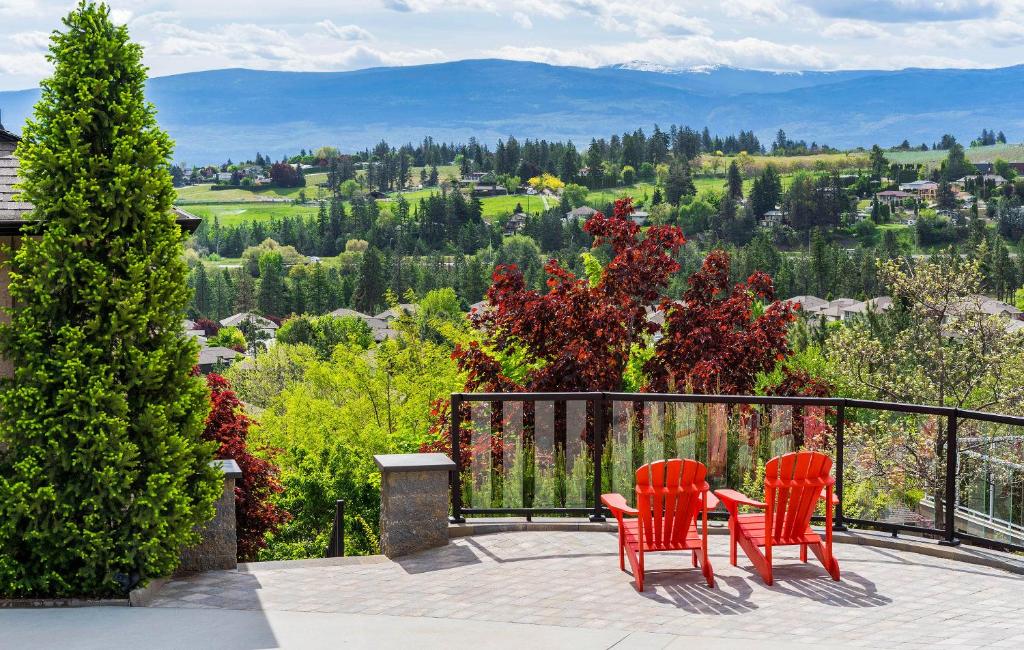 Duas cadeiras vermelhas e uma mesa num pátio com vista. em Sunrise Valley Suite em West Kelowna