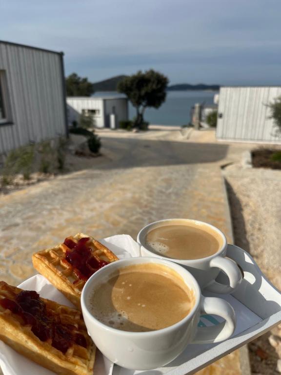 two cups of coffee and two waffles on a table at BUQEZ ECO RESORT - Beach Villas 2 and 8 - Seaview, new wifi! in Drage