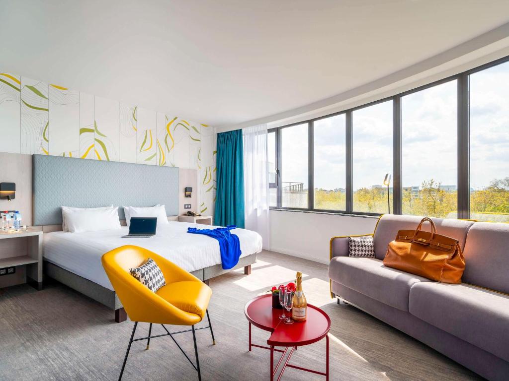 um quarto de hotel com uma cama e um sofá em Mercure Antwerp City Centre em Antuérpia