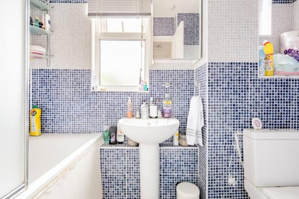 baño de azulejos azules con lavabo y bañera en Buzz Crib en Londres