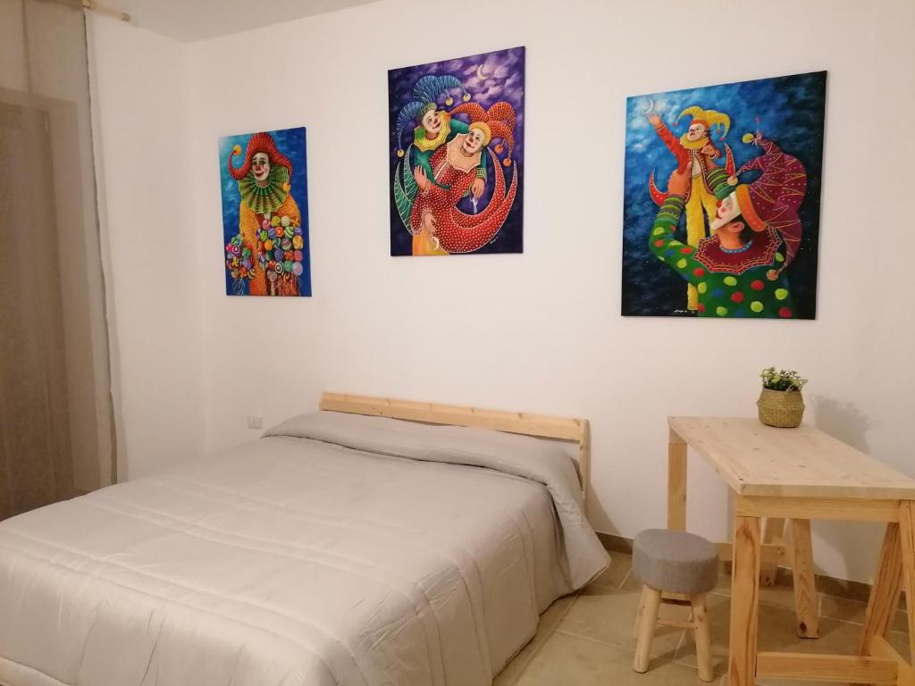 a bedroom with three paintings on the wall at Soffio Del Sud in Crispiano