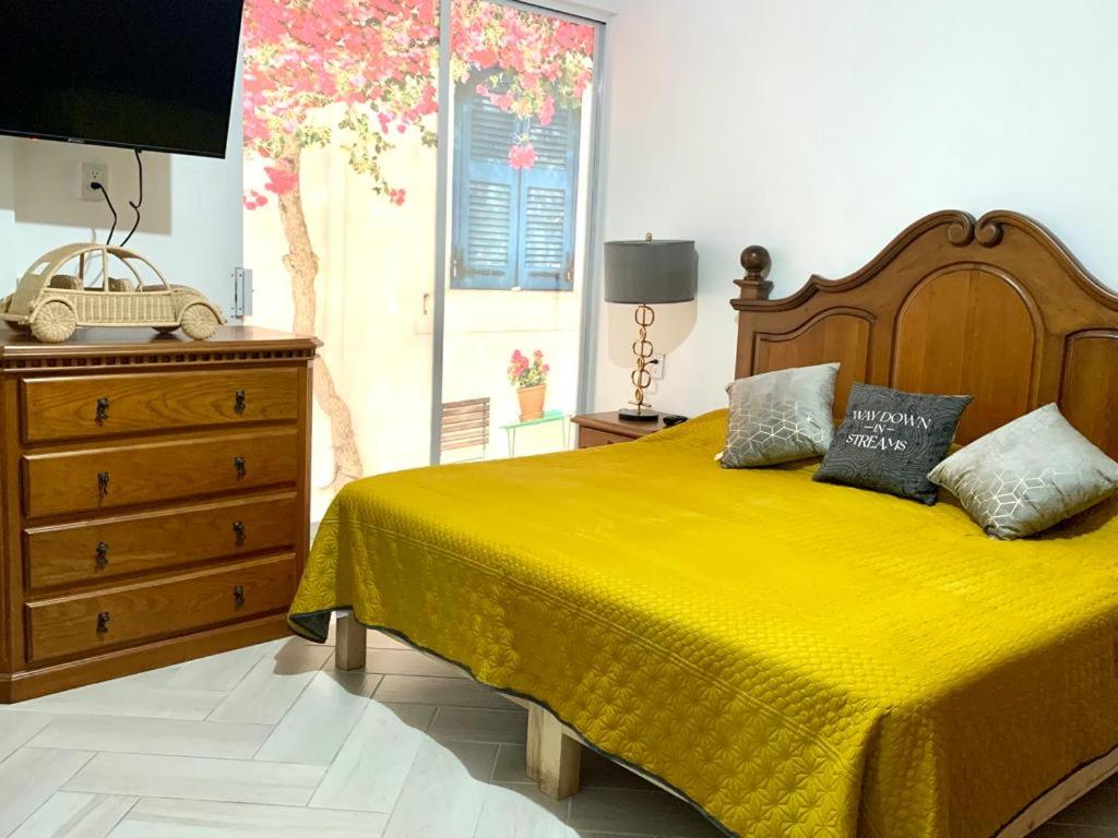 - une chambre avec un lit jaune et une commode dans l'établissement Bungamvilias Apartment, à Uruapan del Progreso