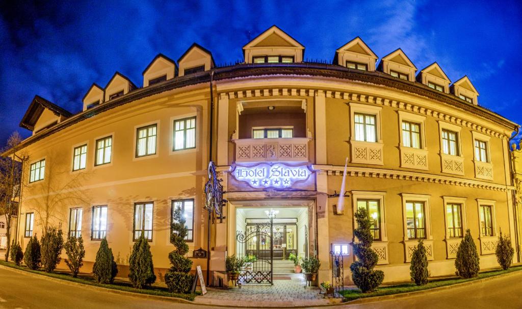 d'un grand bâtiment jaune avec un panneau. dans l'établissement Hotel Slavia, à Salonta